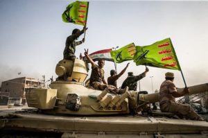 Fighters raise the flags of Iraq and the Popular Mobilization Forces.