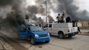 Al-Qaida fighters patrol in a commandeered police truck passing burning police vehicles in front of the main provincial government building, in Fallujah, 40 miles (65 kilometers) west of Baghdad, Iraq, Jan. 1, 2014. /AP