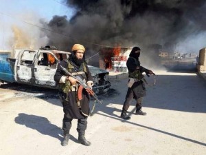Islamic State of Iraq and the Levant militants stand near a burning police vehicle in Iraq's Anbar province.  /Militant website via AP