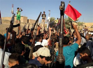 Shiite tribal fighters raise their weapons and chant slogans against the al-Qaida-inspired Islamic State of Iraq and the Levant (ISIL) in the east Baghdad neighborhood of Kamaliya, Iraq on June 15.  /AP