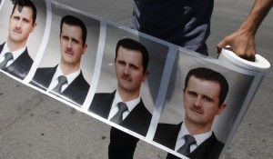 A demonstrator with photos of Syrian President Bashar Assad at a rally in Damascus.  /Khaled al-Hariri/Reuters
