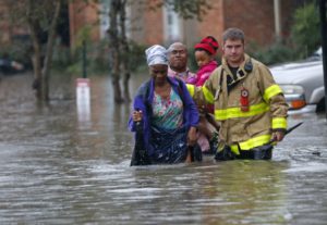 A member of the St. George Fire Department helps residents wade through floodwaters in Baton Rouge.