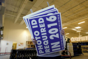 A worker carries a sign that will be displayed at a polling place that will inform voters of the new voter ID law that goes into effect in 2016 at the Mecklenburg County Board of Elections warehouse in Charlotte