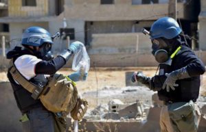 Investigators take samples from sand near a part of a missile that was suspected of carrying chemical agents near Ain Terma, Syria on Aug. 28, 2014. /AP