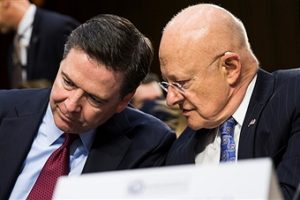 National Intelligence James Clapper (R) whispers to FBI Director James Comey during a Senate Intelligence Committee hearing in Washington, USA on February 9, 2016. /Getty Images