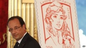 French President Francois Hollande stands next to the newly unveiled official Marianne postal stamp. /AP