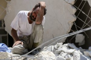 A man waits as Syrian civil defence workers look for survivors under the rubble of a collapsed building following reported air strikes on July 17, 2016 in Aleppo. /AFP/Thaer Mohammed